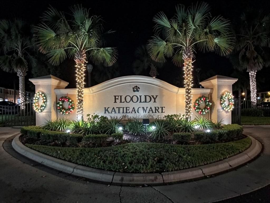 Lit community entrance sign with palms and wreaths